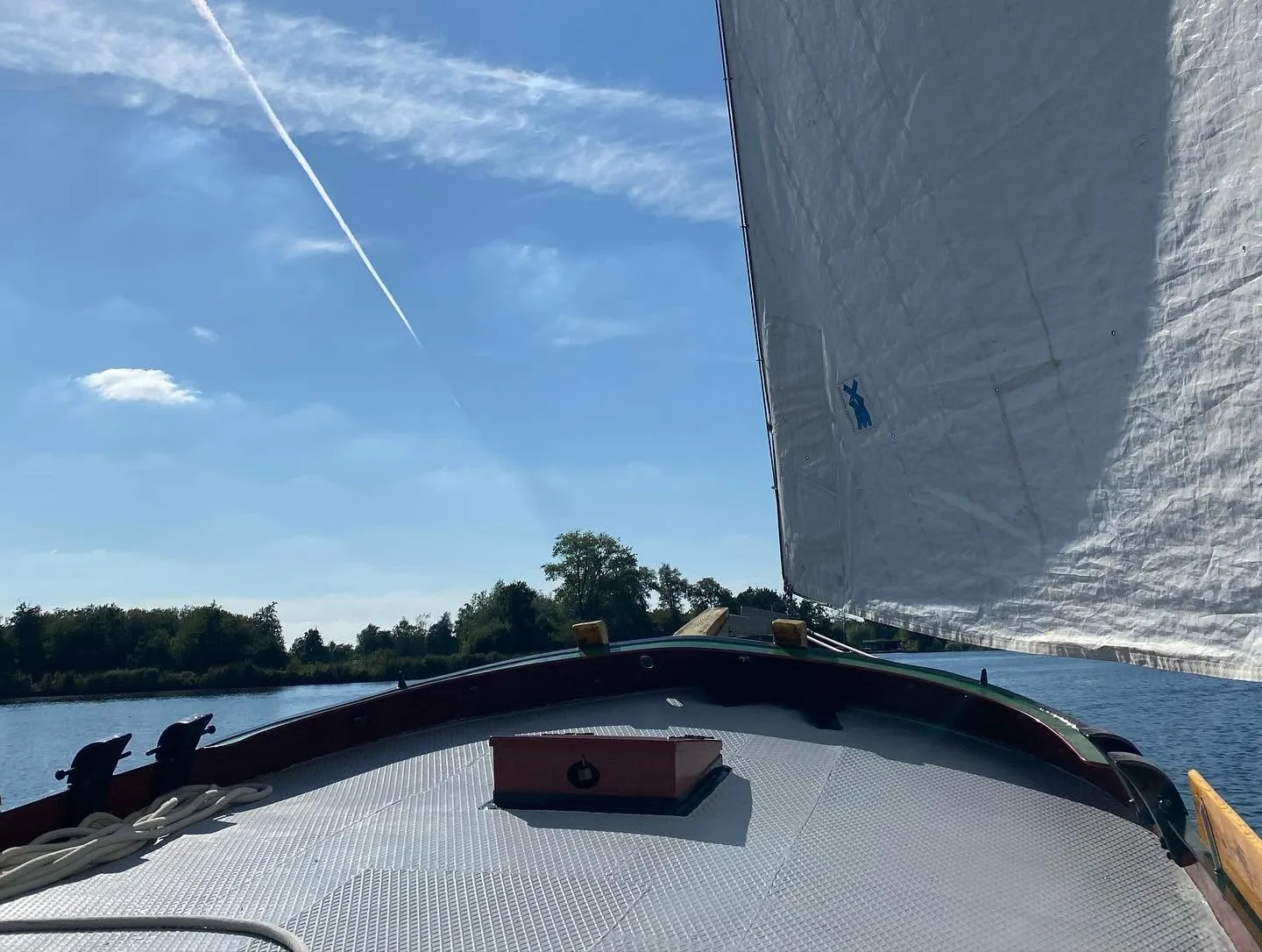 Uitzicht vanaf het dek, langs de giek en het witte zeil over het water.